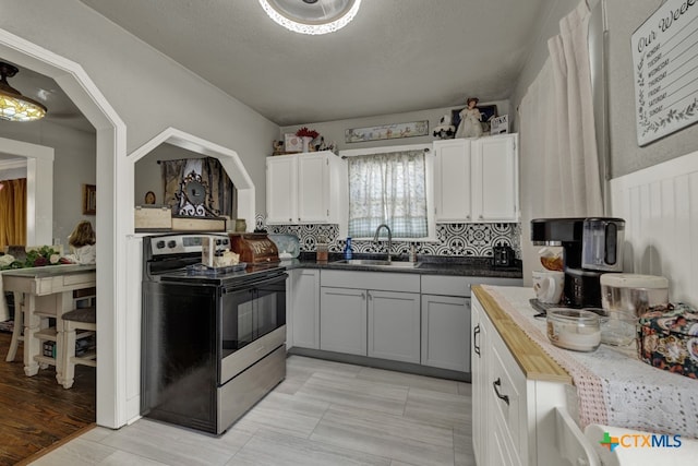 kitchen featuring white cabinetry, sink, a textured ceiling, wood counters, and electric range