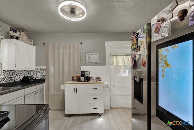 kitchen featuring white cabinetry, black stove, and a textured ceiling