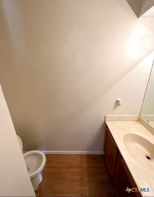 bathroom with vanity, toilet, and hardwood / wood-style floors