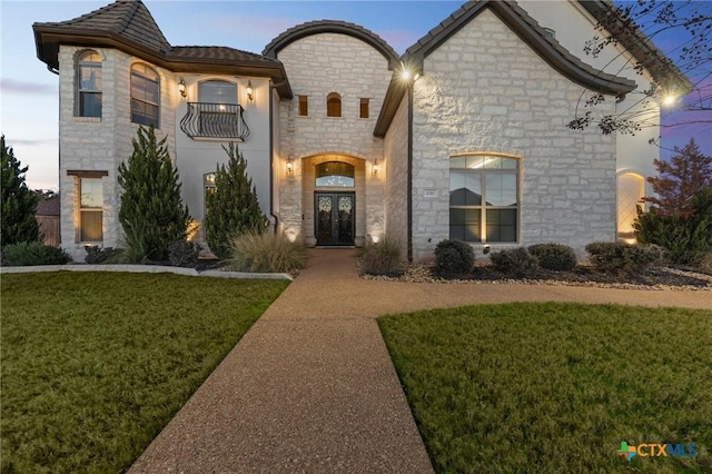 french country inspired facade featuring french doors and a yard