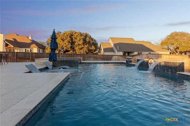 pool at dusk featuring pool water feature