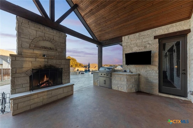 view of patio / terrace with an outdoor stone fireplace, grilling area, and an outdoor kitchen