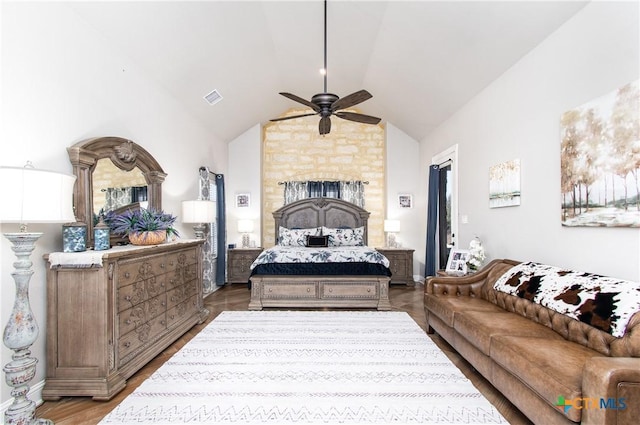 bedroom with hardwood / wood-style floors, a large fireplace, vaulted ceiling, and ceiling fan