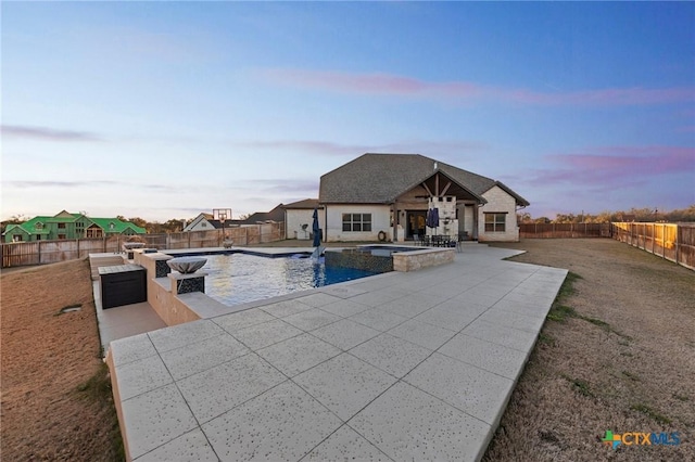 pool at dusk featuring an in ground hot tub and a patio