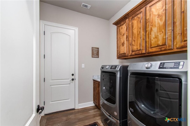 laundry room with cabinets, washing machine and dryer, and dark wood-type flooring