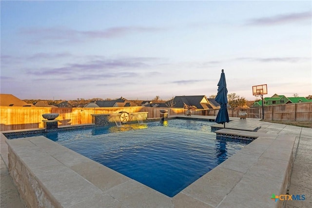 pool at dusk featuring pool water feature