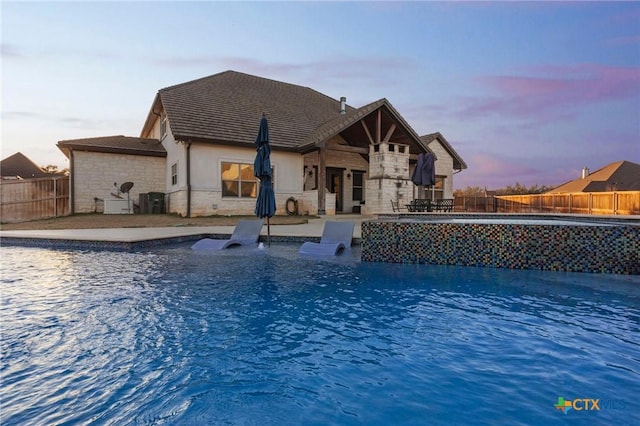 pool at dusk featuring a patio area