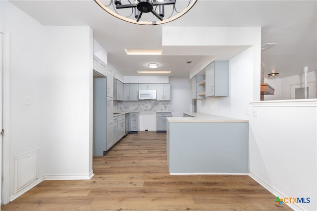 kitchen with a chandelier, tasteful backsplash, light hardwood / wood-style flooring, and gray cabinetry