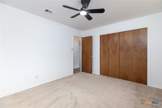 unfurnished bedroom featuring ceiling fan, light colored carpet, and a closet