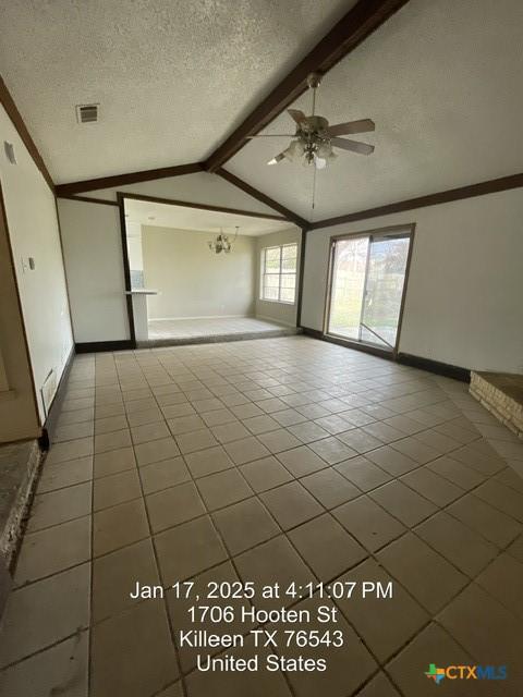 spare room with ceiling fan, vaulted ceiling with beams, tile patterned floors, and a textured ceiling