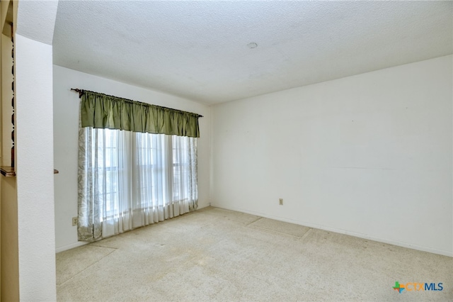 unfurnished room featuring a textured ceiling and light carpet