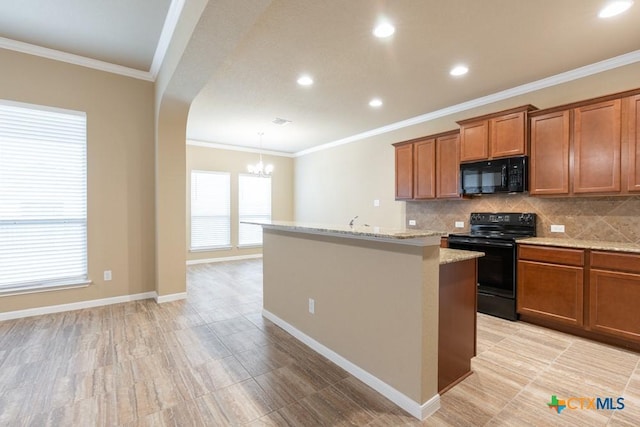 kitchen with pendant lighting, decorative backsplash, light stone counters, black appliances, and a center island with sink