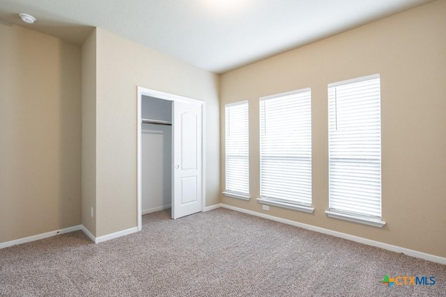 unfurnished bedroom with a closet and light carpet