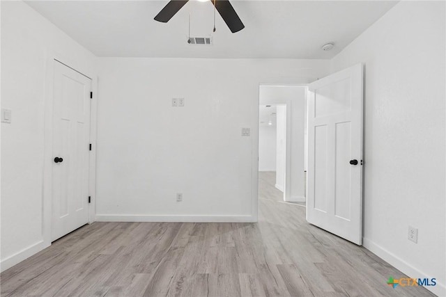 spare room featuring light wood-style floors, visible vents, and baseboards