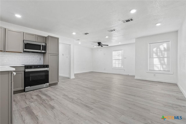 kitchen featuring gray cabinets, light countertops, electric stove, and stainless steel microwave