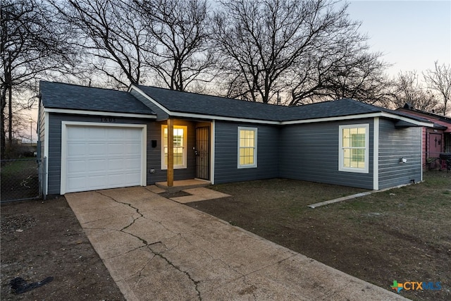 ranch-style home featuring driveway, roof with shingles, and an attached garage