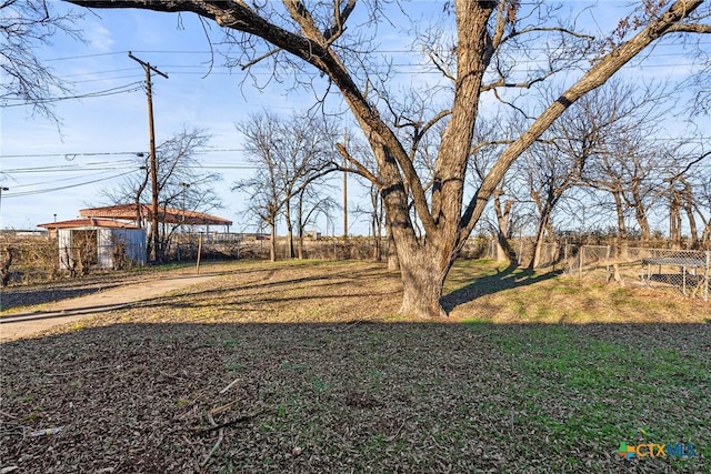 view of yard featuring dirt driveway and fence