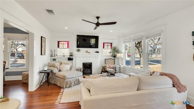 living room with a brick fireplace, dark hardwood / wood-style flooring, and ceiling fan