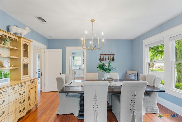 dining area featuring sink, light hardwood / wood-style flooring, and a chandelier