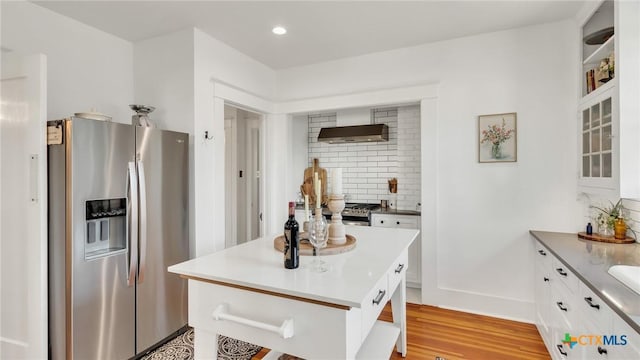 kitchen with white cabinets, a kitchen island, backsplash, stainless steel fridge with ice dispenser, and light hardwood / wood-style flooring