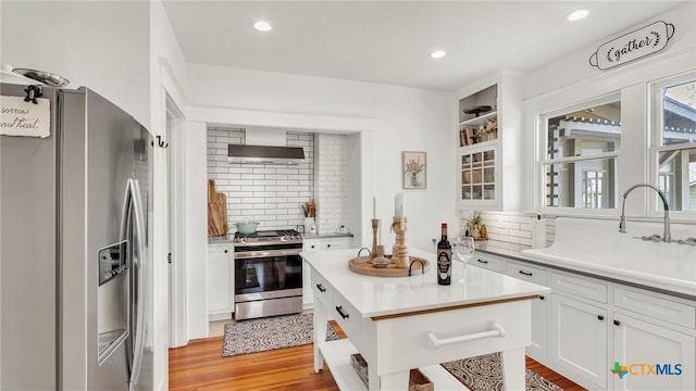 kitchen featuring tasteful backsplash, light wood-type flooring, stainless steel appliances, and white cabinetry