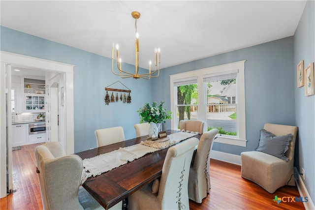 dining space featuring wood-type flooring and a chandelier