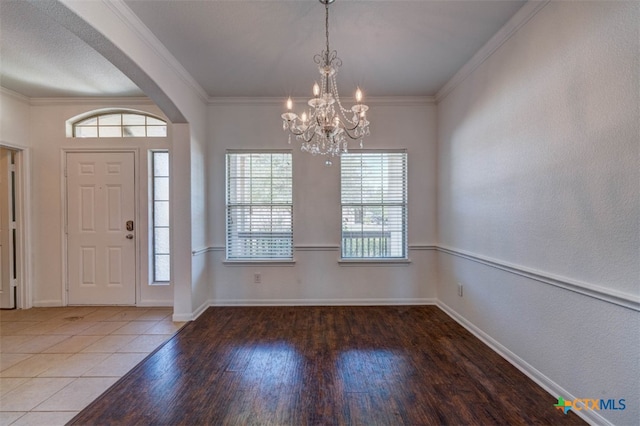 foyer featuring a wealth of natural light, ornamental molding, a notable chandelier, and hardwood / wood-style flooring