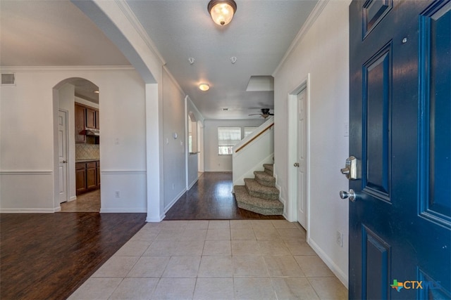 entrance foyer featuring ceiling fan, ornamental molding, and light wood-type flooring