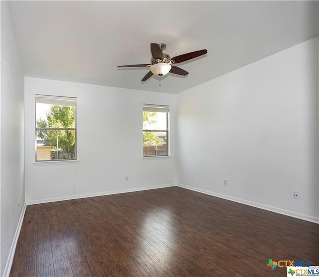 spare room featuring plenty of natural light, ceiling fan, and dark hardwood / wood-style flooring