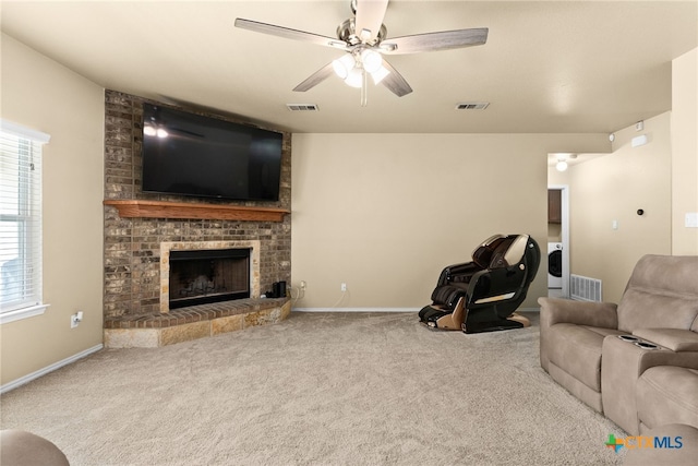 living room featuring washer / clothes dryer, carpet flooring, ceiling fan, and a brick fireplace