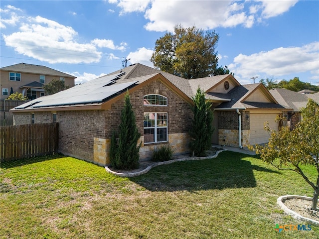 view of front of home with a garage, a front yard, and solar panels