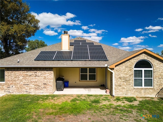 rear view of property featuring solar panels, a patio, and a yard