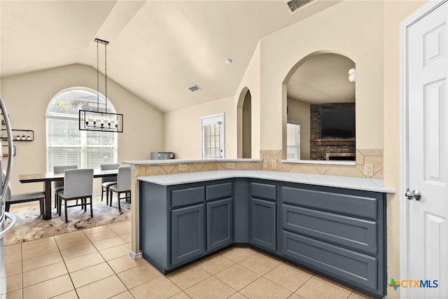 kitchen featuring hanging light fixtures, light tile patterned flooring, vaulted ceiling, and kitchen peninsula