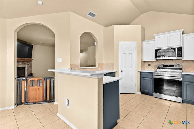 kitchen featuring stainless steel appliances, white cabinets, kitchen peninsula, light tile patterned flooring, and backsplash