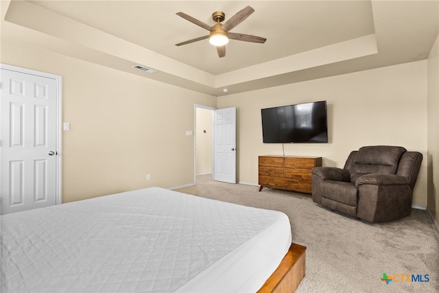 carpeted bedroom with ceiling fan and a tray ceiling