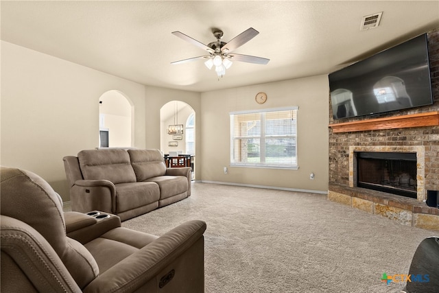 carpeted living room featuring a brick fireplace and ceiling fan