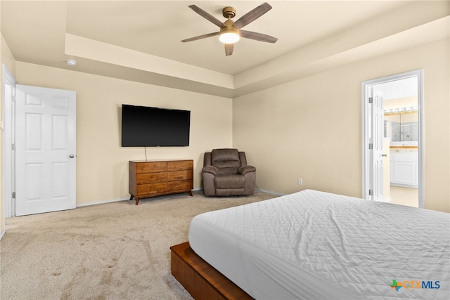 carpeted bedroom featuring connected bathroom, a tray ceiling, and ceiling fan