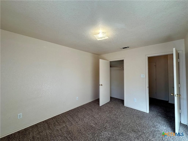 unfurnished bedroom featuring dark colored carpet, a textured ceiling, and a closet