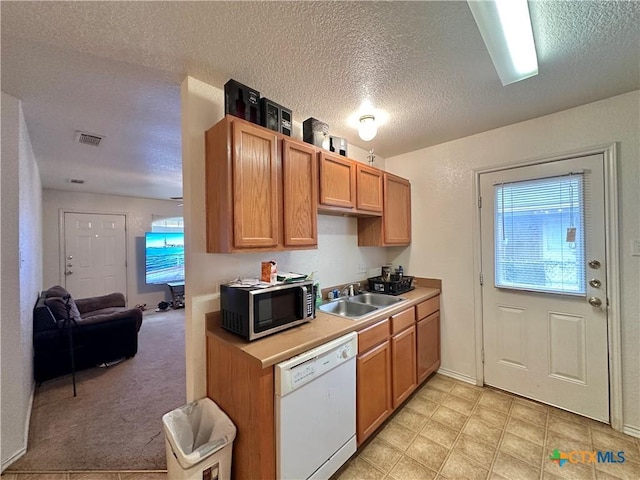 kitchen with white dishwasher, sink, light carpet, and a textured ceiling