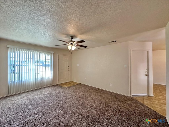 empty room with ceiling fan, carpet floors, and a textured ceiling