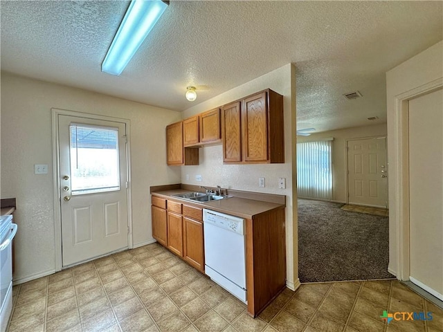 kitchen featuring dishwasher, sink, light colored carpet, and a textured ceiling