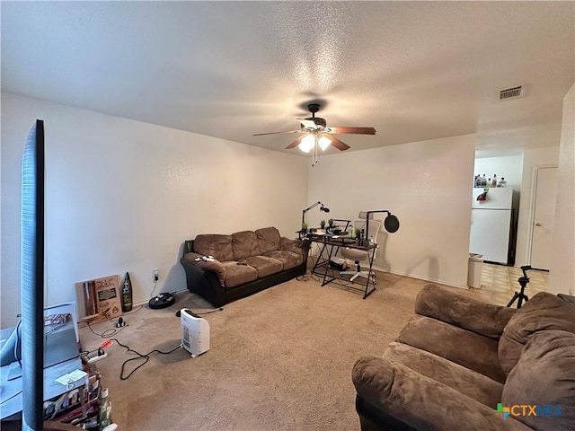 carpeted living room with ceiling fan and a textured ceiling