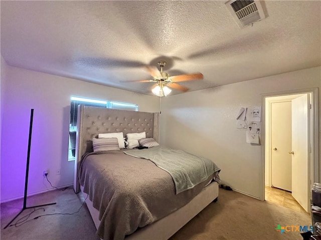 carpeted bedroom featuring ceiling fan and a textured ceiling