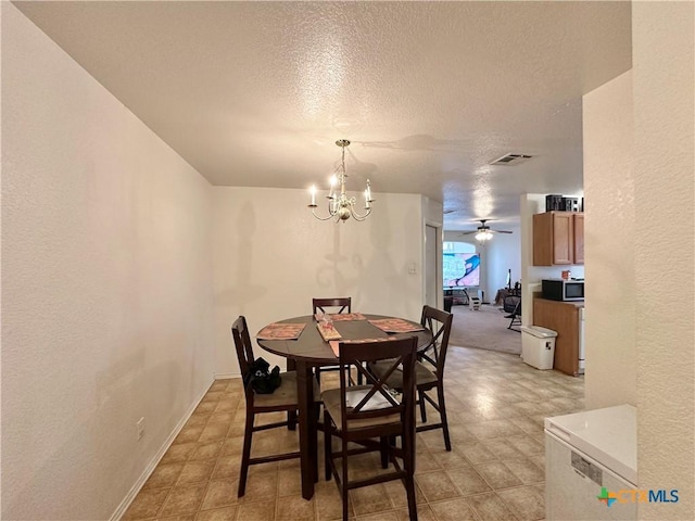 dining room featuring ceiling fan with notable chandelier and a textured ceiling