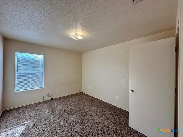 unfurnished room featuring dark carpet and a textured ceiling