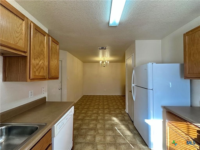 kitchen featuring a textured ceiling, sink, white appliances, and a notable chandelier