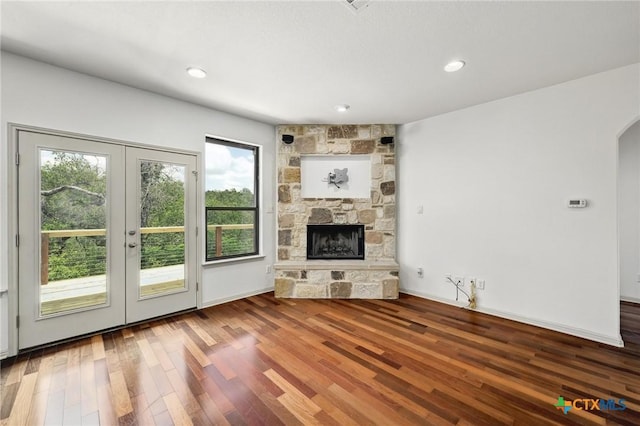 14424 Tuscola Cir, Austin, TX 78734 - unfurnished living room featuring arched walkways, a stone fireplace, wood finished floors, french doors, and recessed lighting