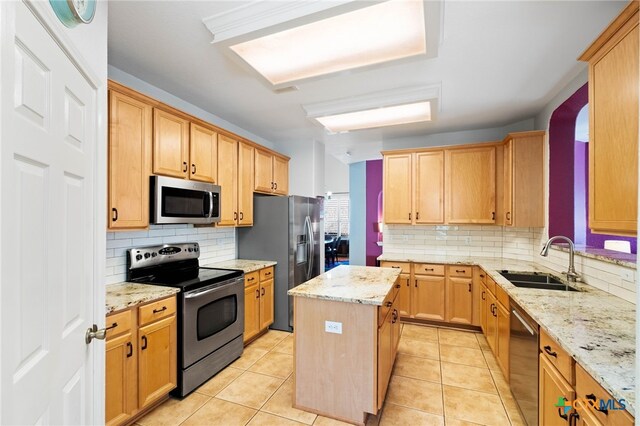 kitchen featuring backsplash, sink, light stone countertops, appliances with stainless steel finishes, and a kitchen island