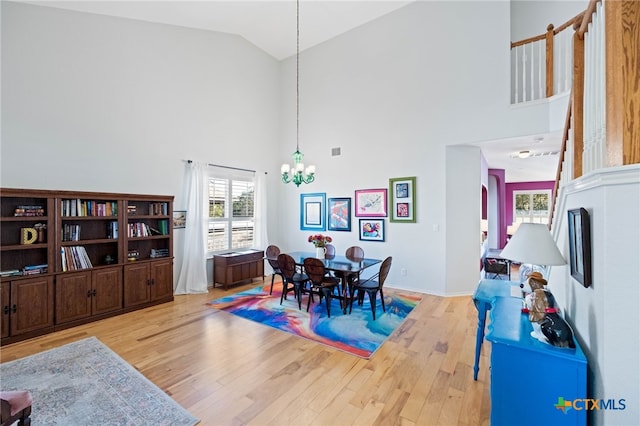 dining space featuring an inviting chandelier, high vaulted ceiling, and light hardwood / wood-style flooring