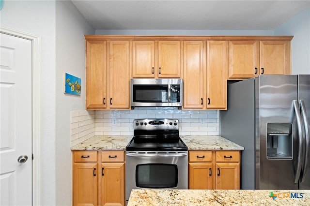 kitchen featuring tasteful backsplash, light stone counters, and appliances with stainless steel finishes